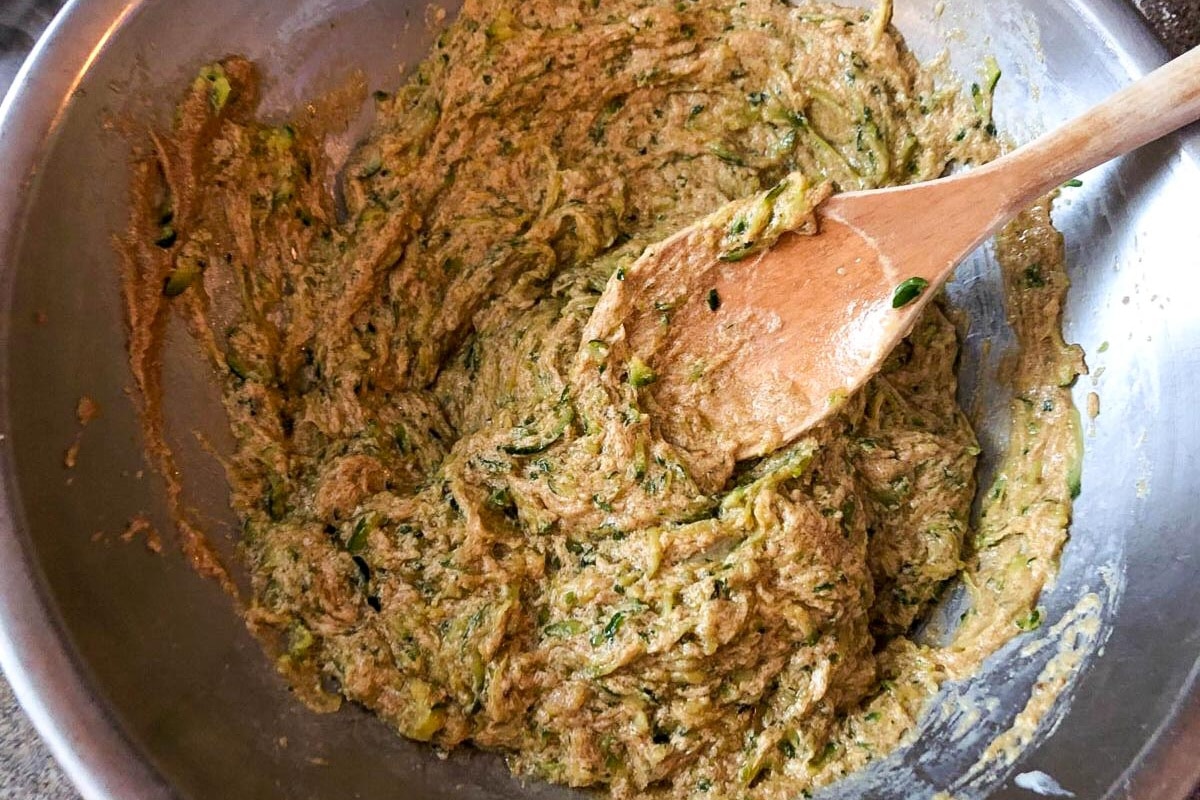 Zucchini mixed with butter and other wet ingredients in a bowl