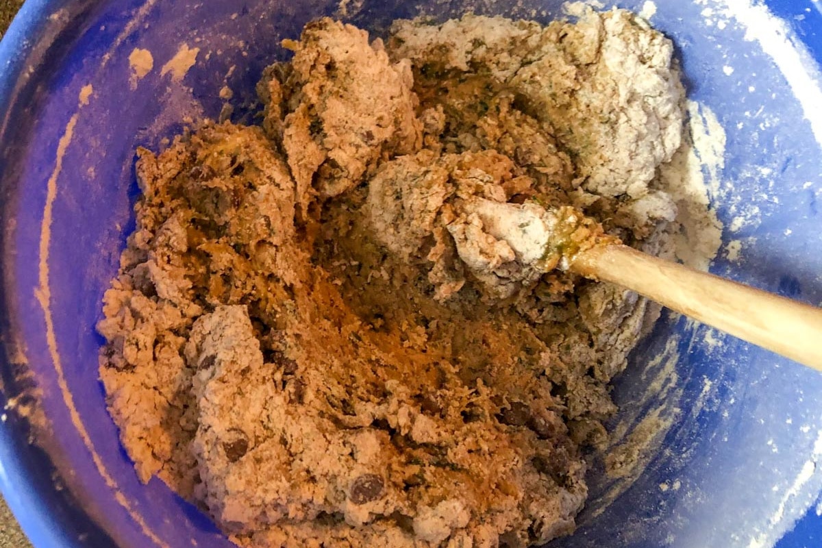 Dry and wet ingredients mixed together in bowl with wooden spoon.