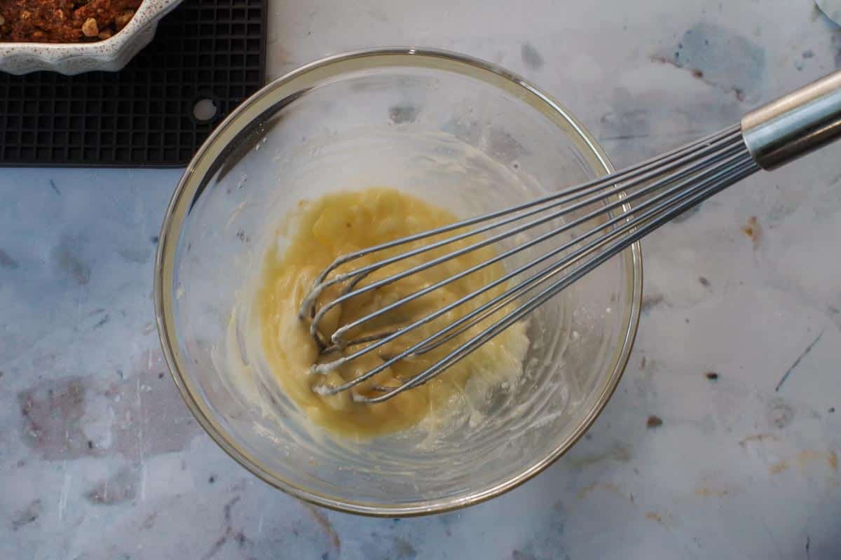 Glaze whisked together in a glass bowl with metal whisk.