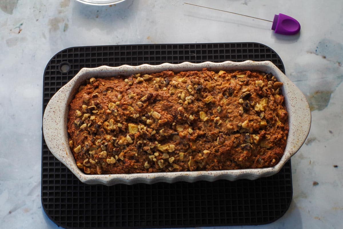 Baked apple walnut bread in pan on trivet.