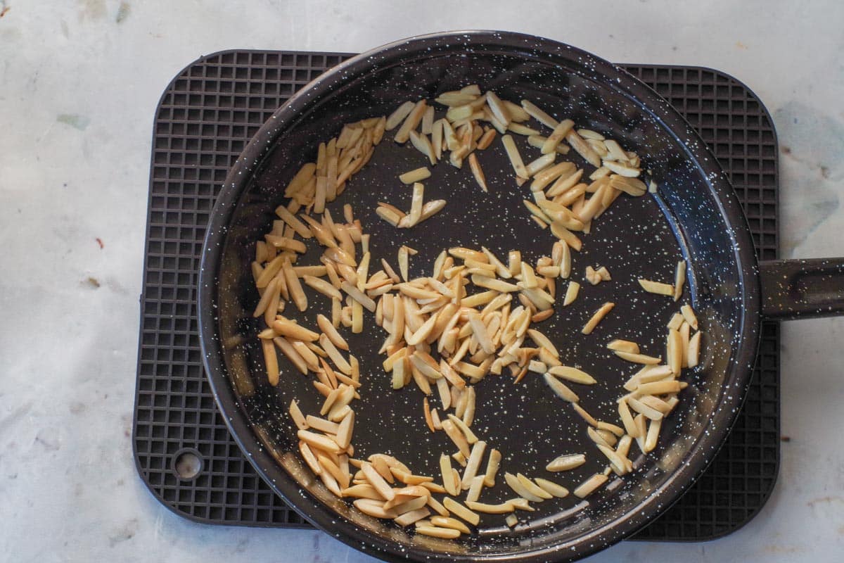 Almonds being toasted in frying pan with oil.
