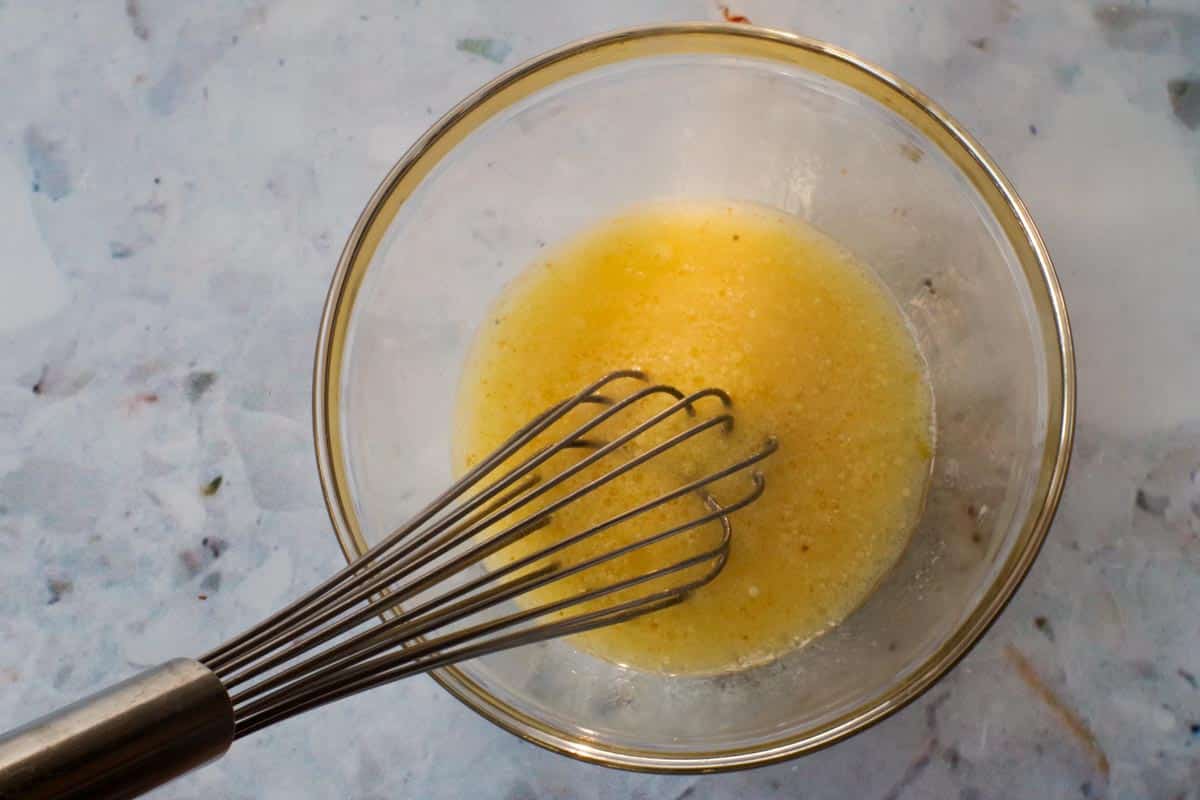 Liquid ingredients whisked together in medium glass bowl with metal whisk.
