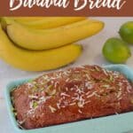 Baked Banana Bread in blue loaf pan with bananas and limes in the background.