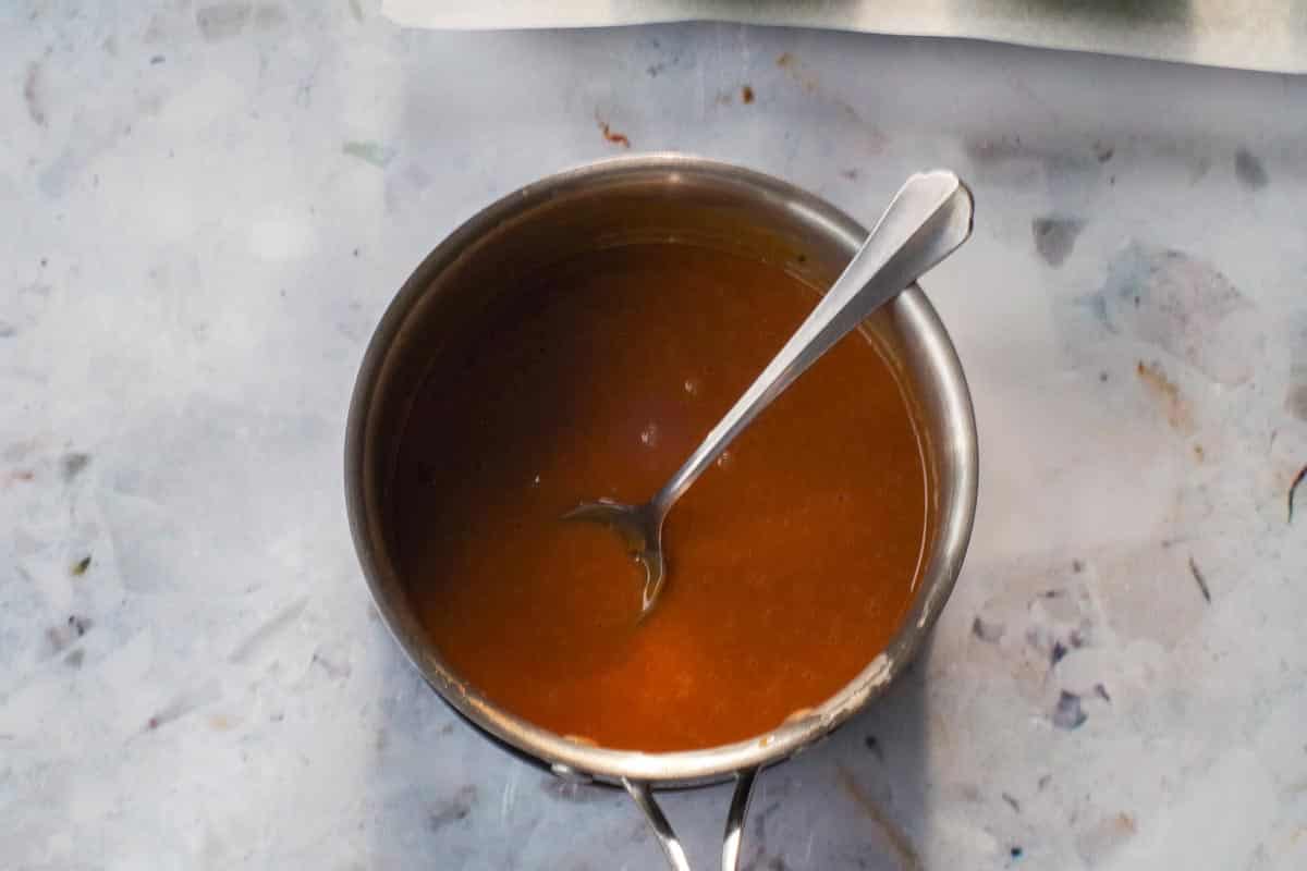 Caramels melted in saucepan with spoon.