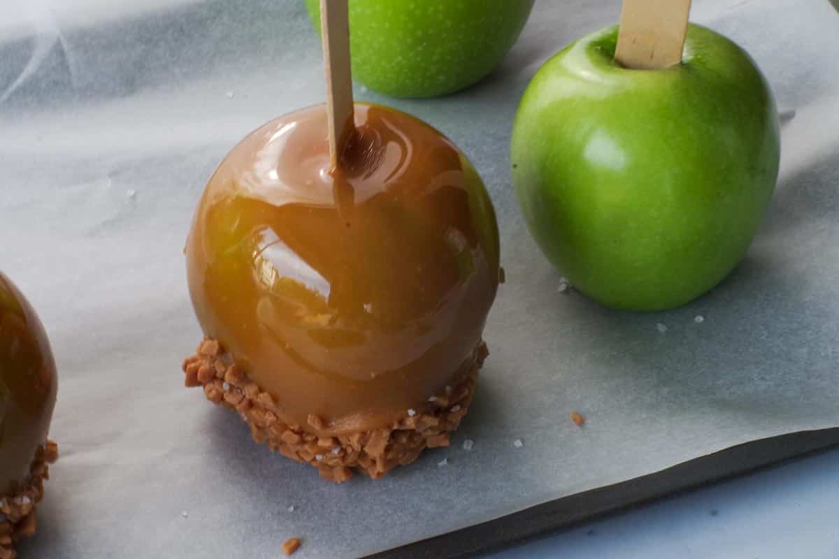 Salted Toffee Caramel apple on a tray with green apples.