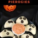 Halloween Pierogies shaped like phantoms on a black plate, with dip in the middle.