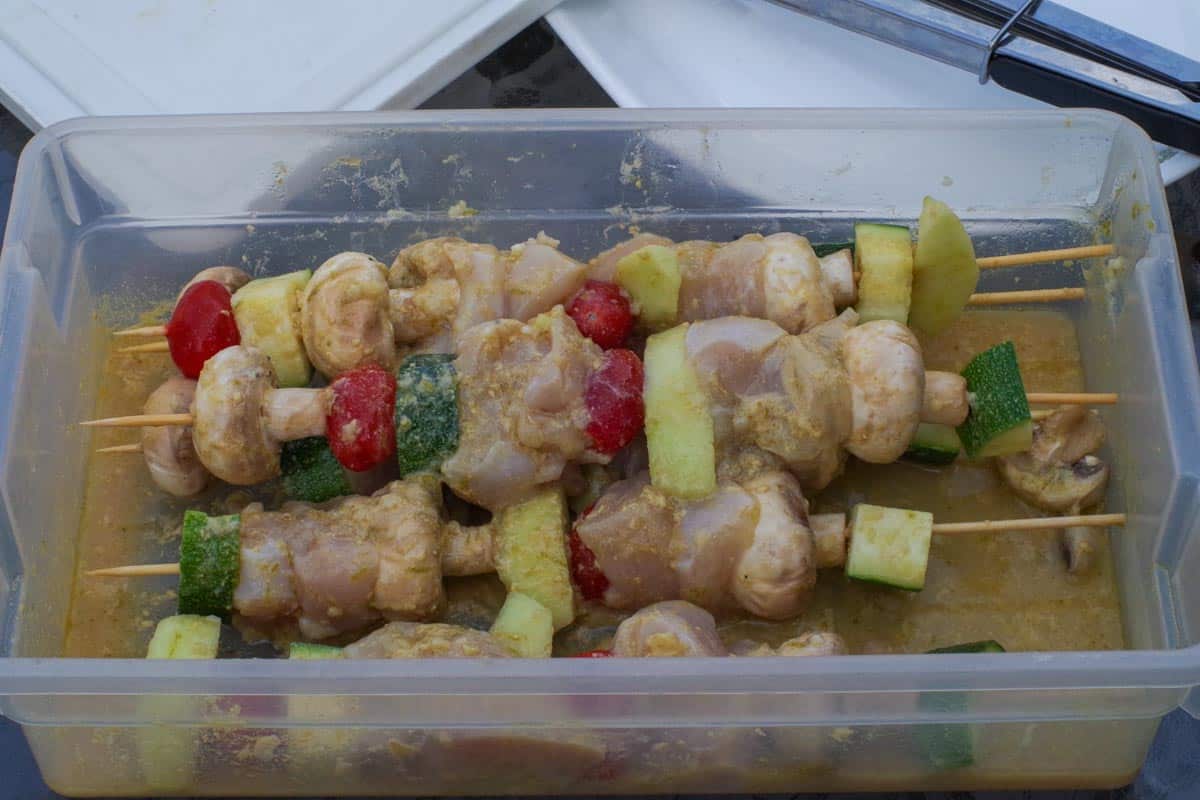 Marinated skewers with marinade poured over the top of the kabobs.