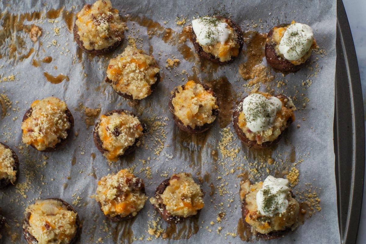 Baked pierogi stuffed mushrooms on a parchment covered baking sheet.