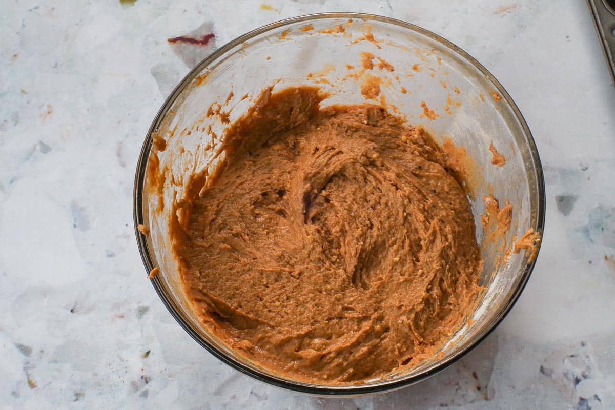Flour added to pumpkin mixture in a glass bowl.