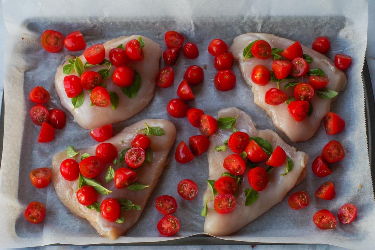 Chicken breasts with basil and grape tomatoes on top.