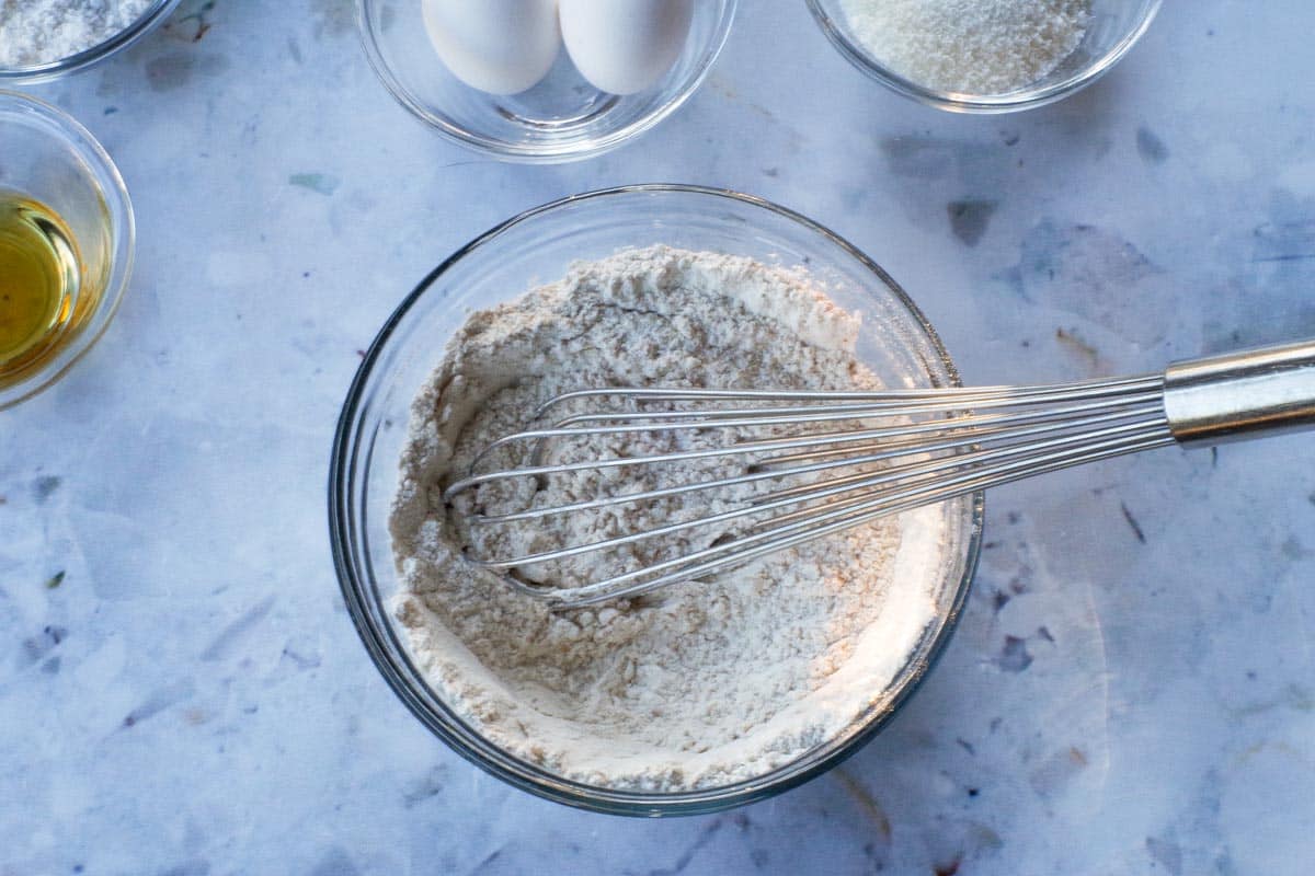 Dry ingredients for Tropical Banana Bread mixed together in glass bowl with metal whisk.