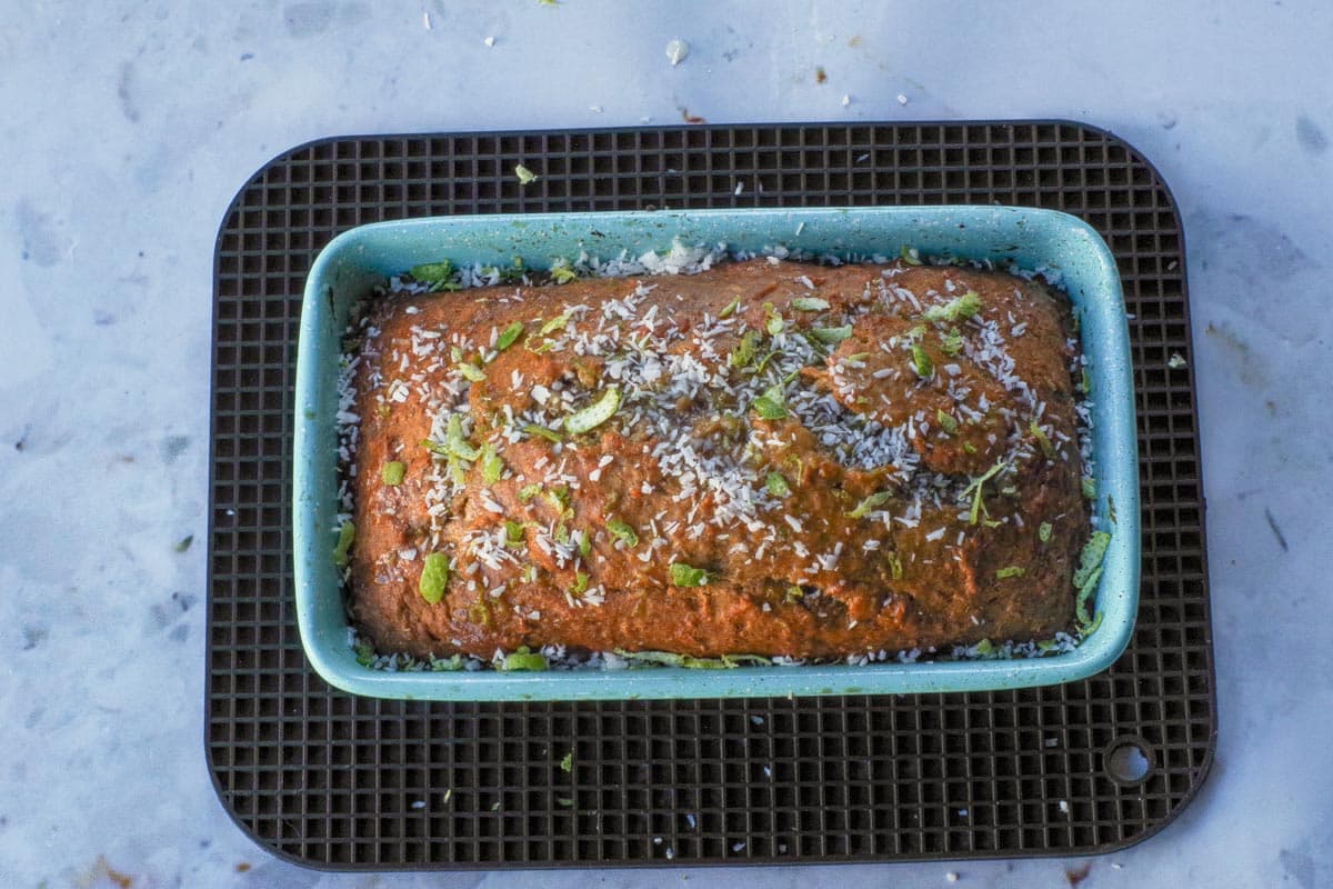 Tropical Banana Bread garnished with coconut and lime in loaf pan.
