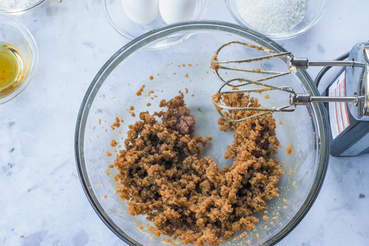 Brown sugar and butter mixed together in a glass bowl with electric mixer.