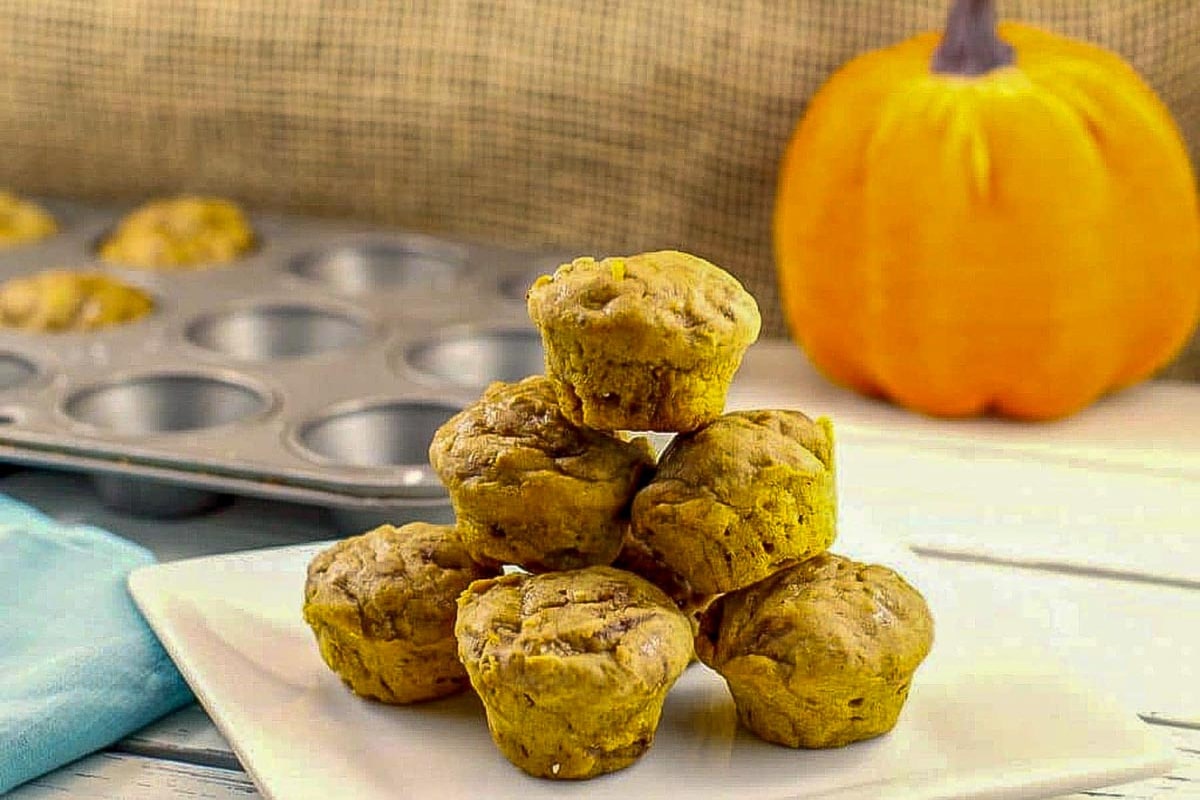 umpkin blondie bites stacked on a white plate with a plush pumpkin in the background