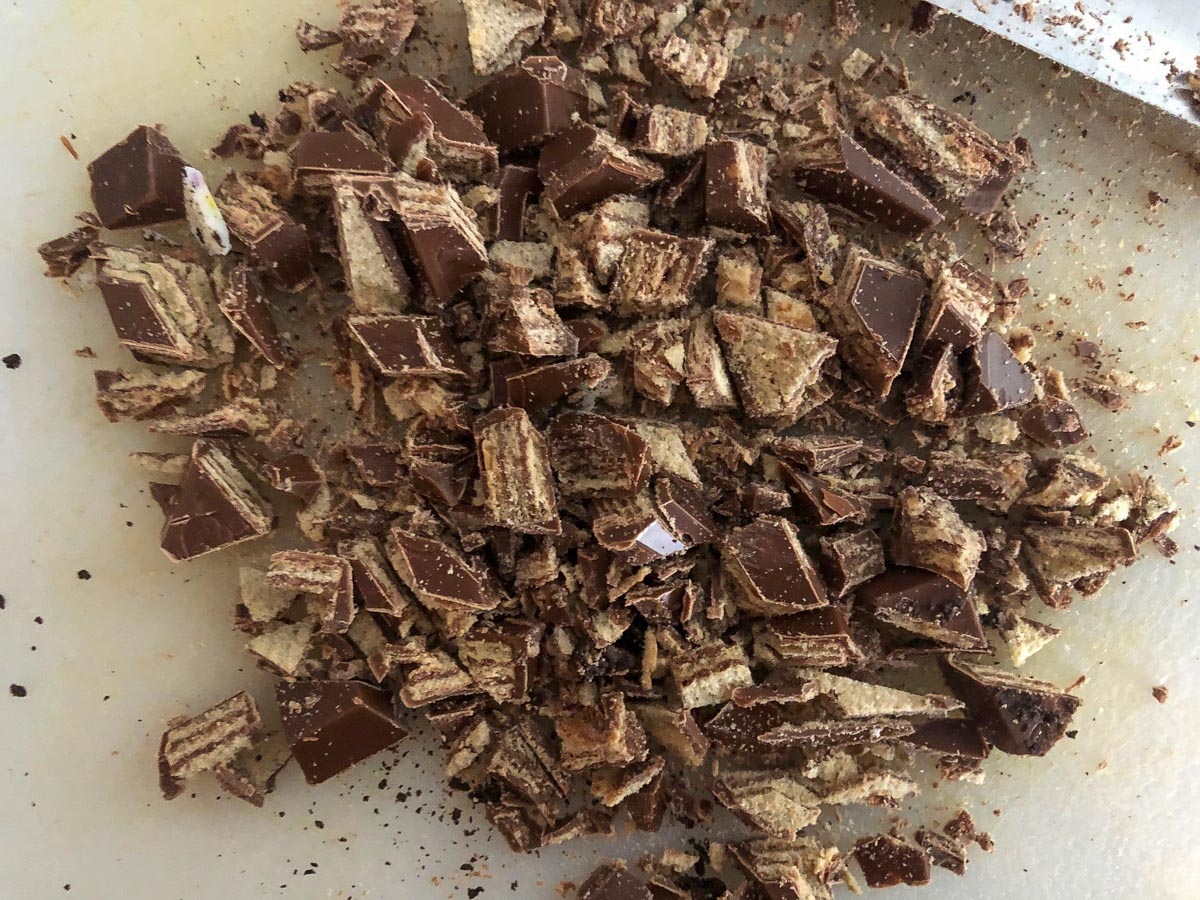 Kit Kat bars chopped up on a cutting board.