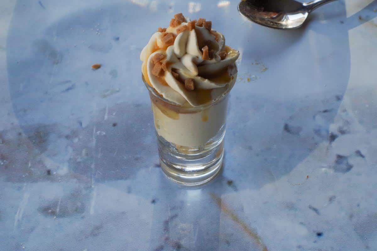 Caramel Apple Betty Dessert Shooter garnished with caramel sauce and toffee bits.