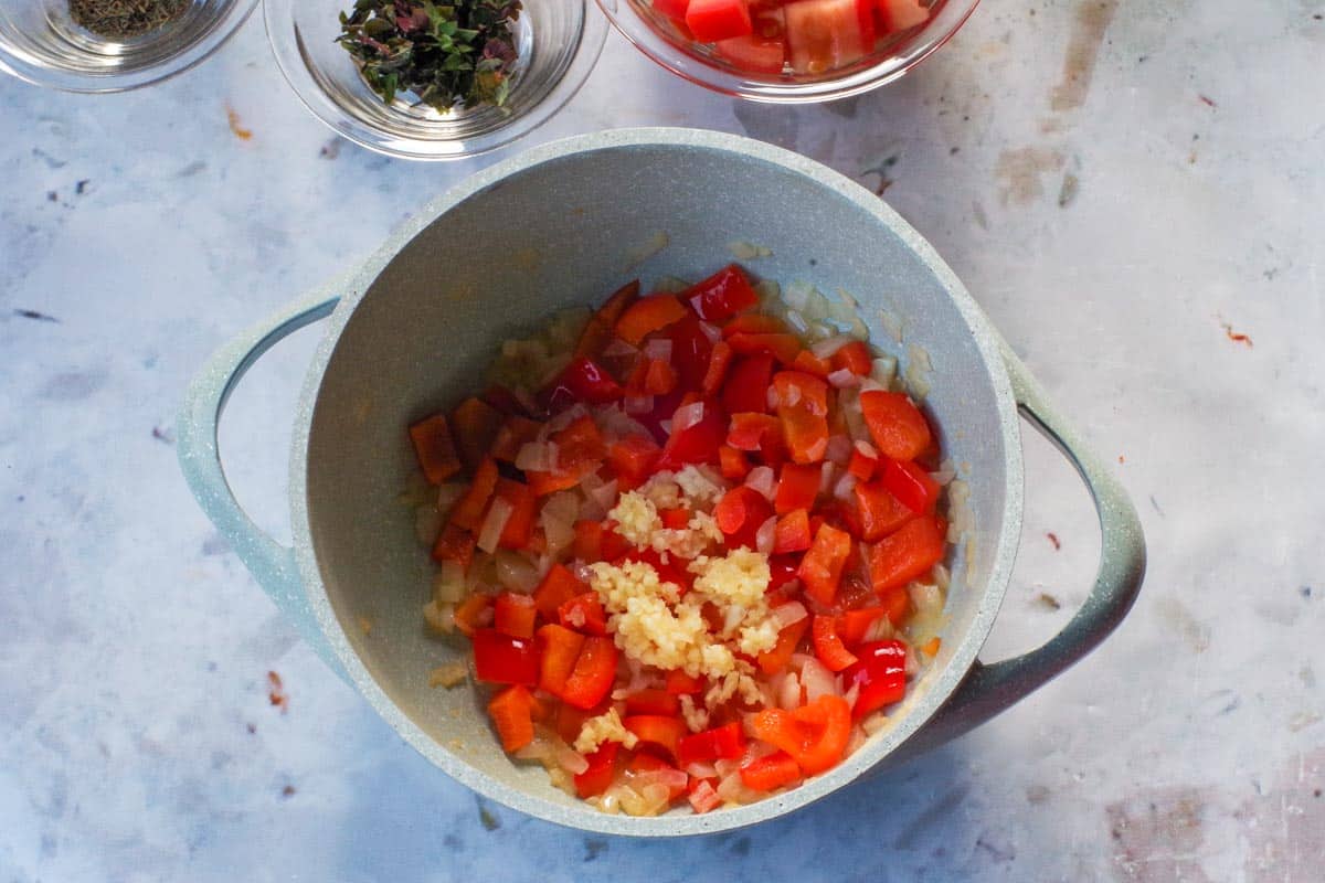 Onions, red peppers and garlic in a pot.