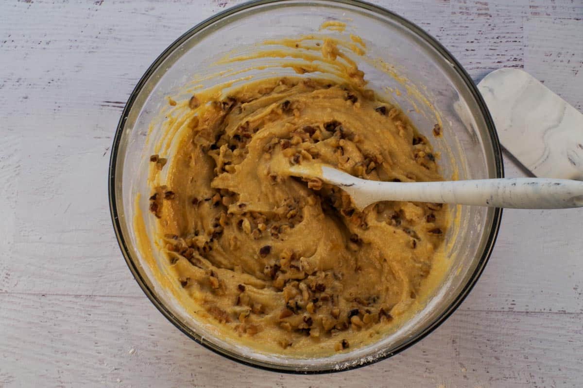 Nuts mixed into pumpkin mixture in large glass bowl.