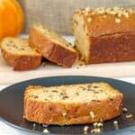 A slice of Dairy-free Pumpkin Bread on a black plate with more in the background.