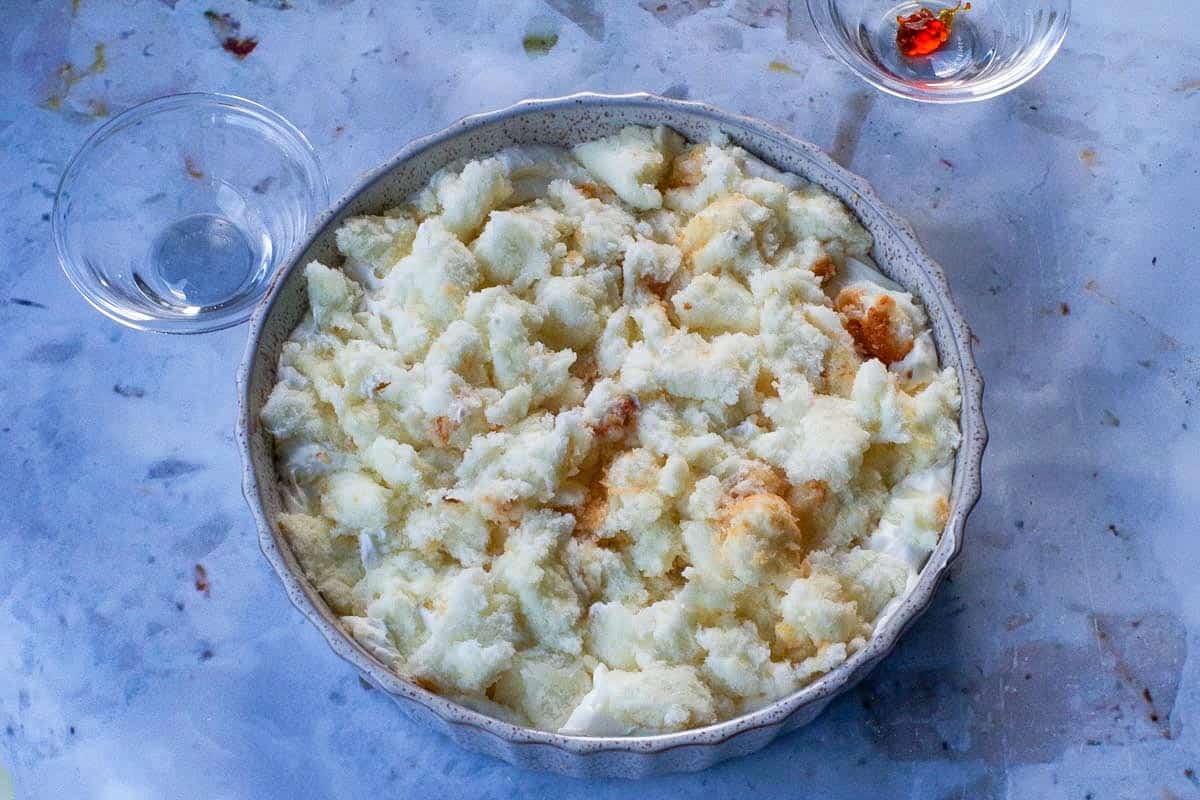 Angel Food Cake broken up over whipped cream layer.
