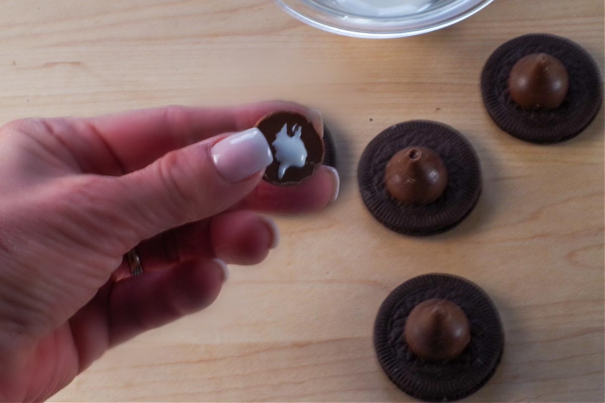 Hershey's kiss with a little royal icing on the bottom being help up.