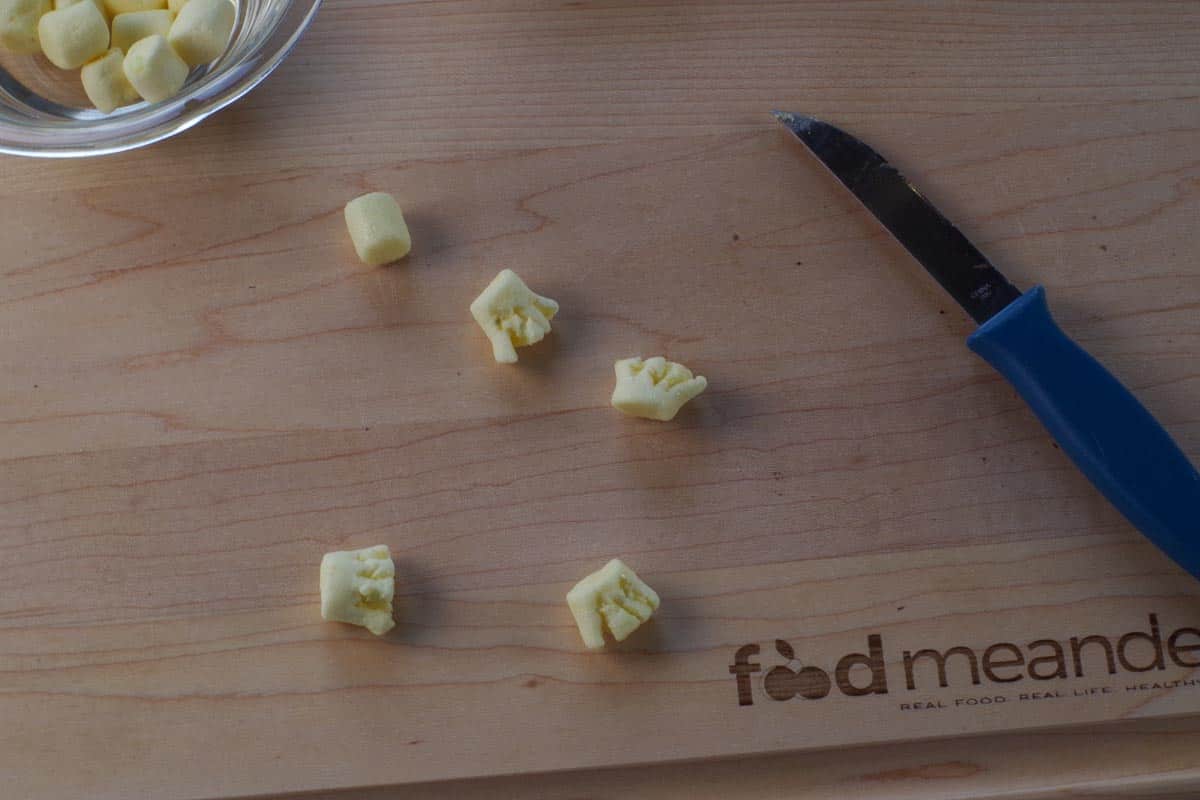 Marshmallows cut into broom ends on a cutting board.