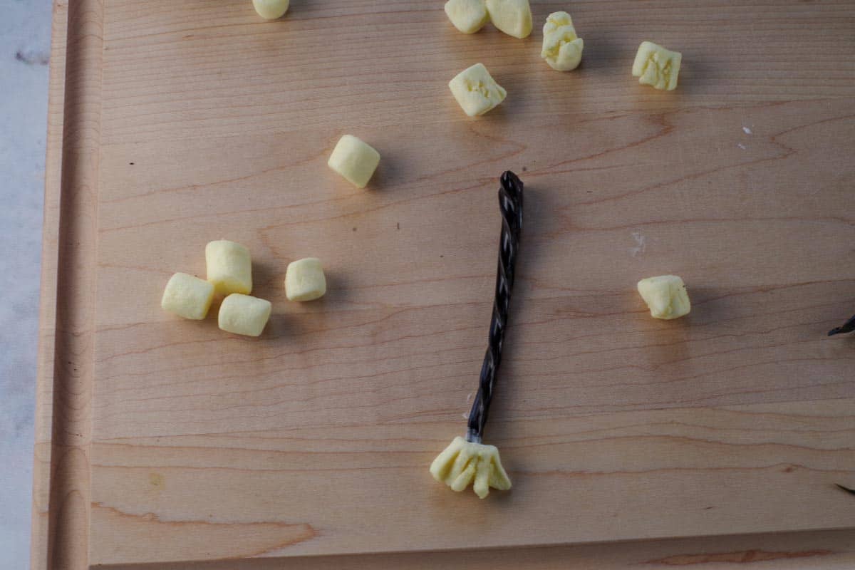 Witch broom made of marshmallow and licorice on a cutting board with more marshallow broom ends.