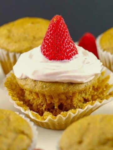 Pancake cupcake with Greek yogurt and strawberry topping, on loosened muffin liner wrapper, with other cupcake pancakes around it