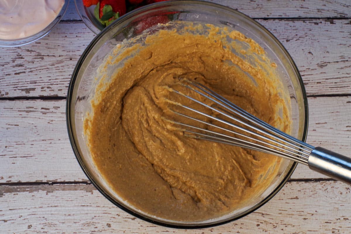 Ingredients whisked together in large glass bowl with metal whisk.
