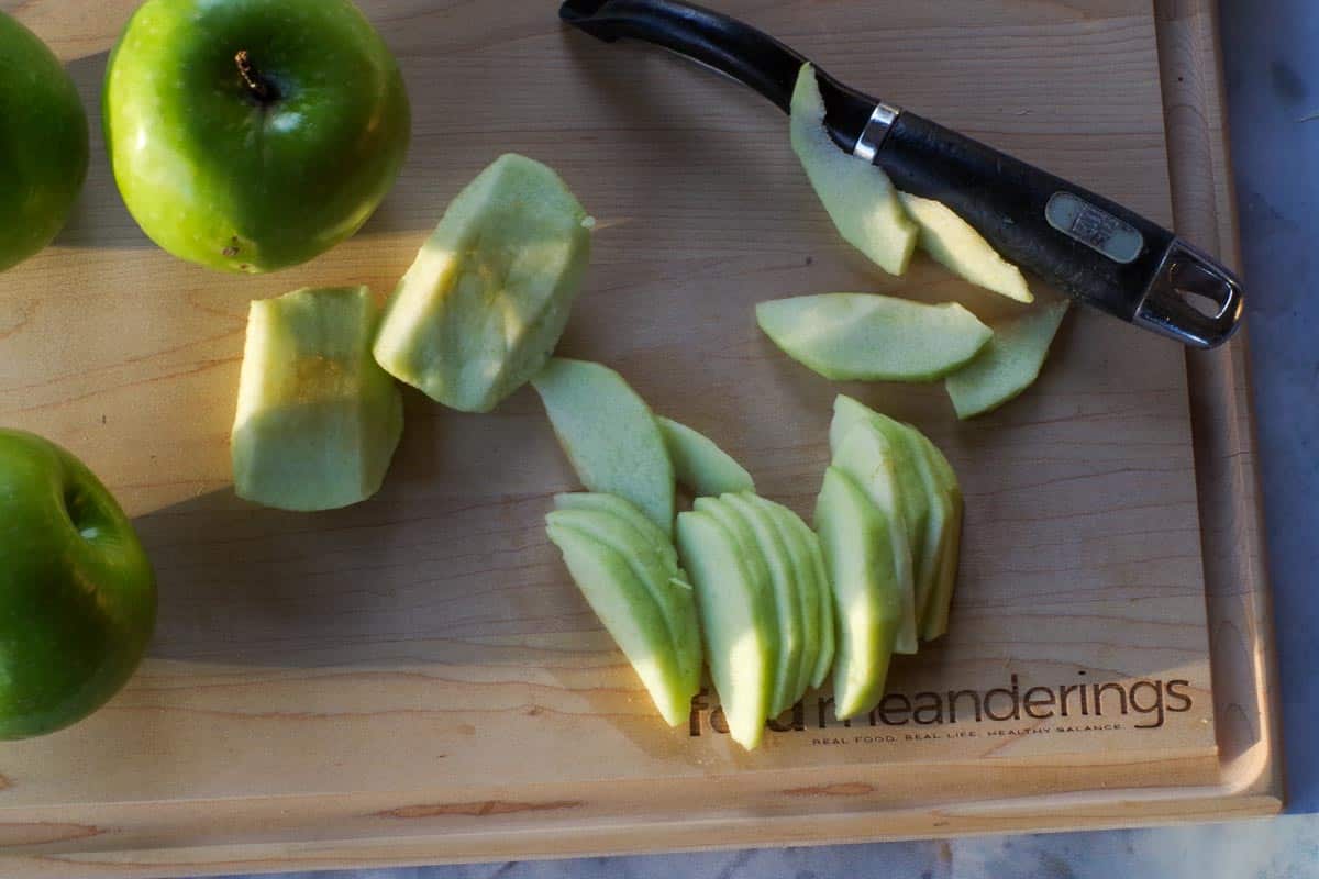 Apples thinly sliced on a cutting board.