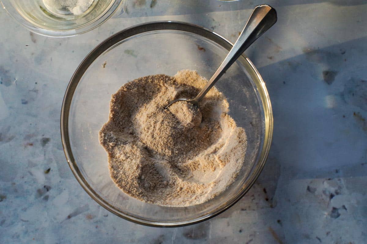 Cinnamon, flour and sugars mixed together in a glass bowl with a spoon.
