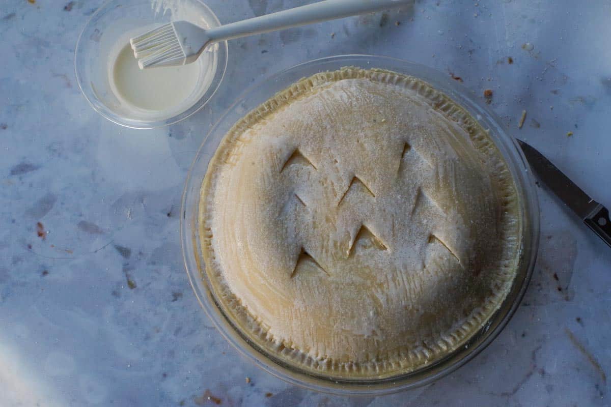 Cream brushed onto the top of pie and pie sprinkled with granulated sugar.