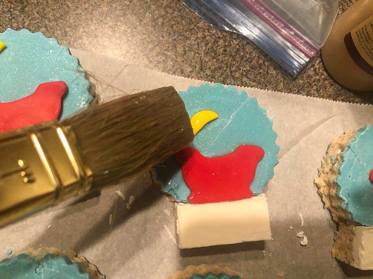 Rice krispie snow globes being painted with confectioners glaze.
