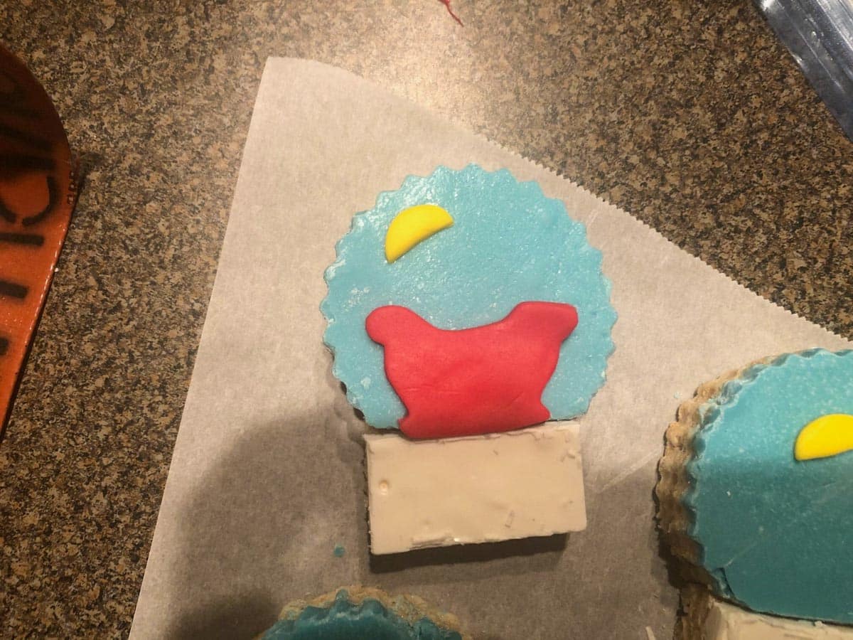Decorations being put on snow globe Christmas rice krispie treats.