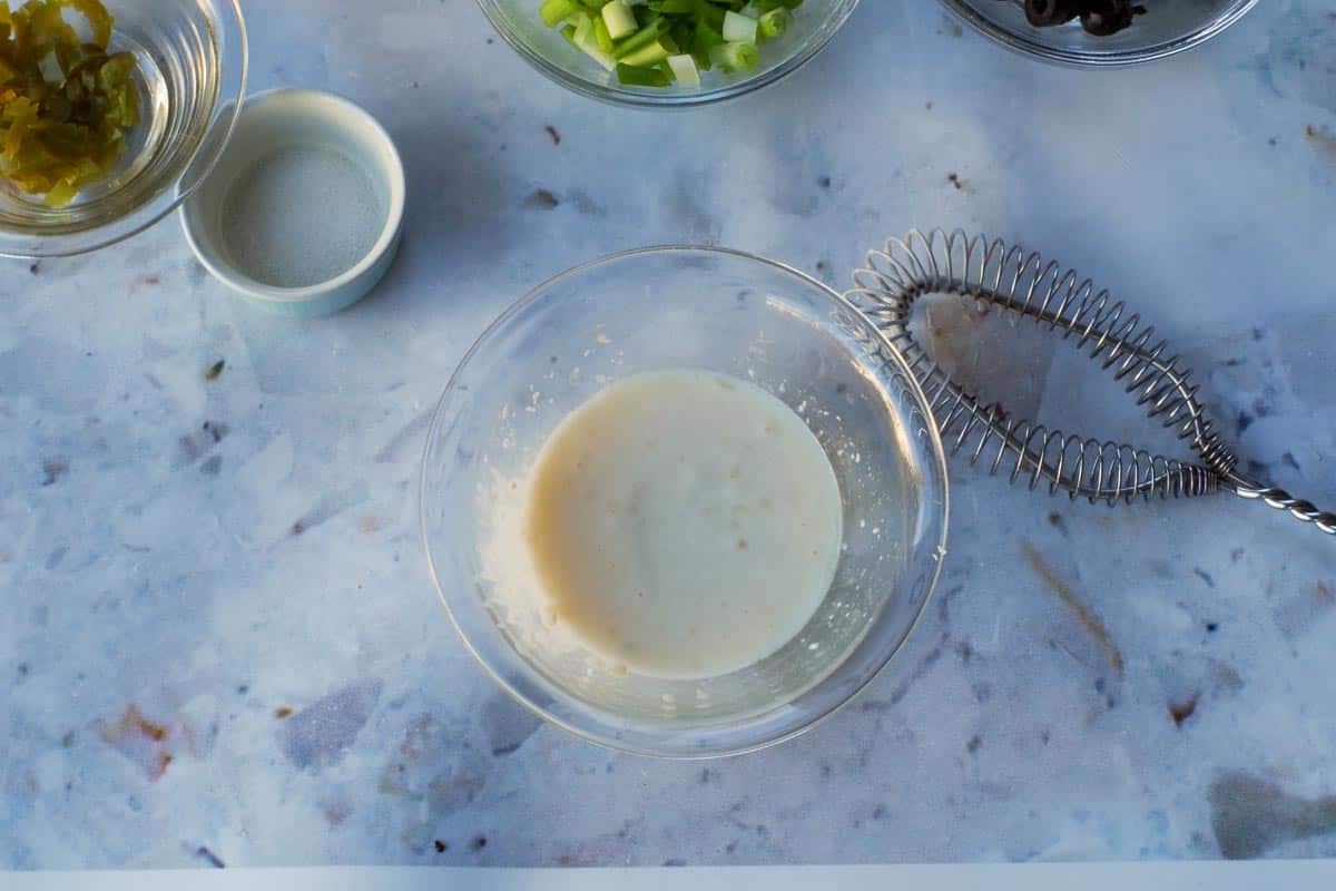 Mayonnaise,garlic lime juice and agave in a glass bowl.