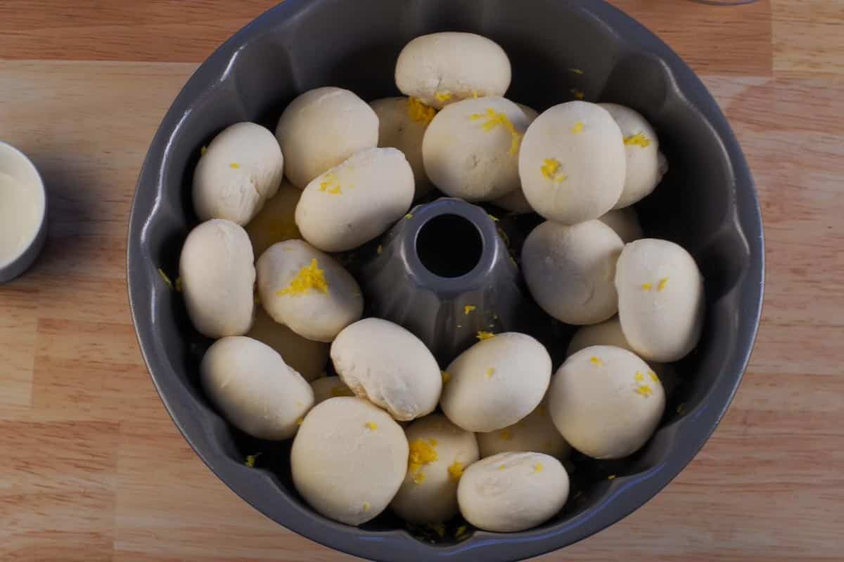 Lemon zest sprinkled over frozen rolls in bundt pan.