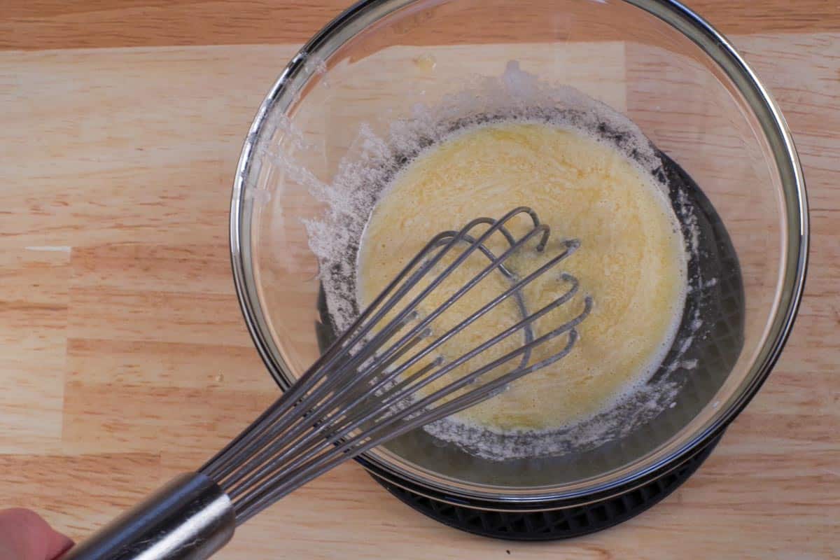 Melted butter and liquid ingredients whisked together in glass bowl.