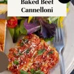 Baked Beef Cannelloni on a plate with salad and garlic toast.