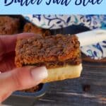 Canadian Butter Tart Slice being held up with a pan of more butter tart slice in the background.