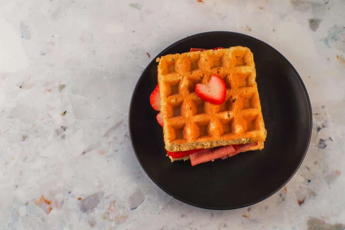 Healthy Chicken Waffle Sandwich on a black plate.