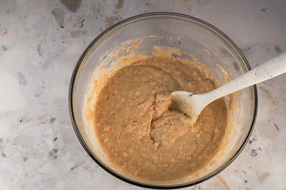 Wet and dry ingredients mixed together in large glass bowl.