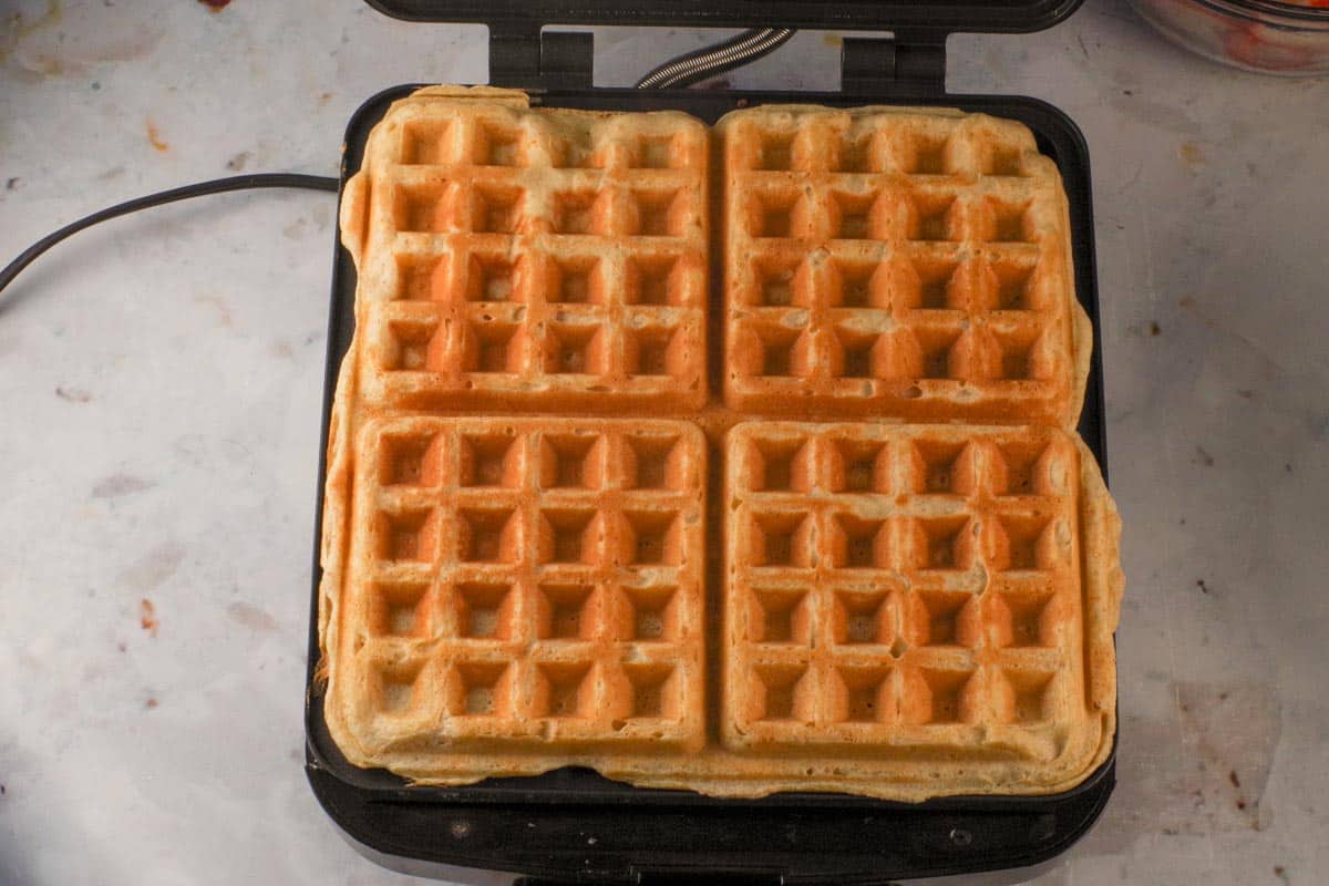 Cooked waffles on a hot waffle iron.