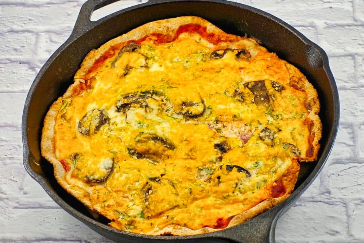 Cooked healthy egg white breakfast pizza in cast iron frying pan.