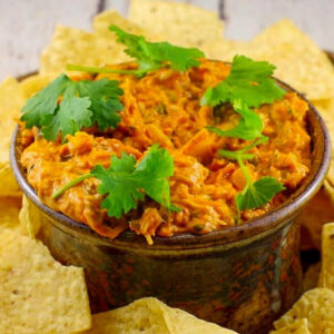 Hot Artichoke Pizza Dip in a bowl with tortilla chips around it on a platter.