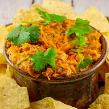 Hot Artichoke Pizza Dip in a bowl with tortilla chips around it on a platter.