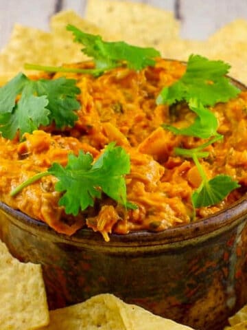 Hot Artichoke Pizza Dip in a bowl with tortilla chips around it on a platter.