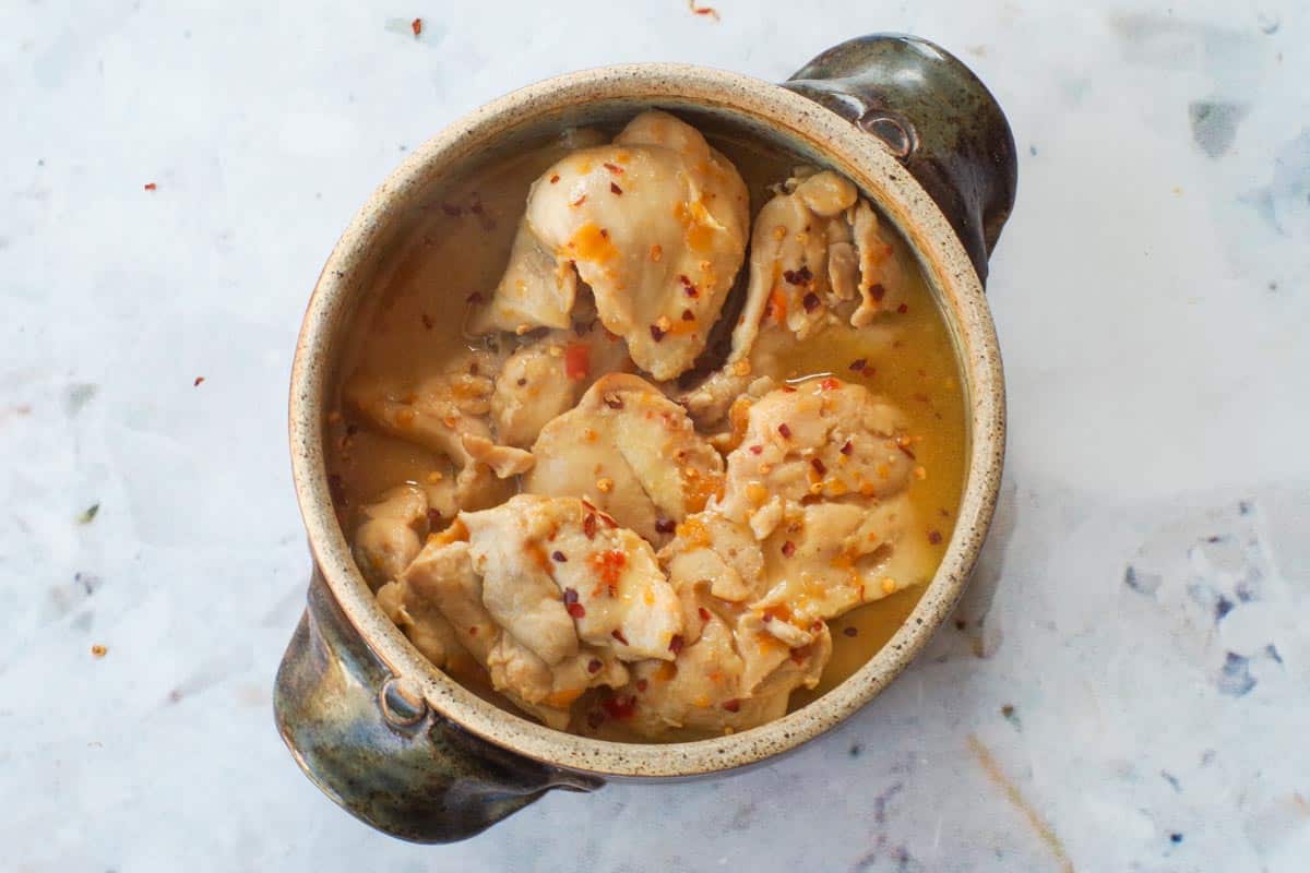 Apricot chicken (with jam) in a pottery dish, garnished.