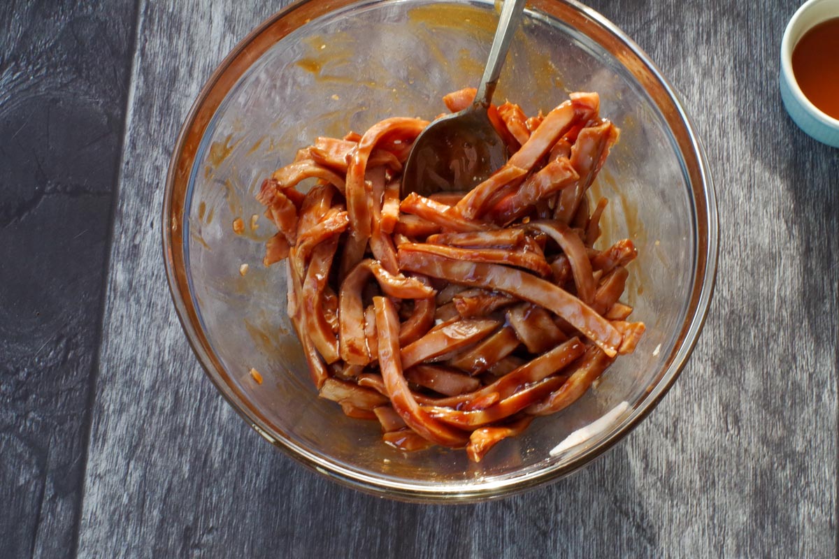 Thinly sliced ham in a glass bowl with hoisin, soy and fish sauces.