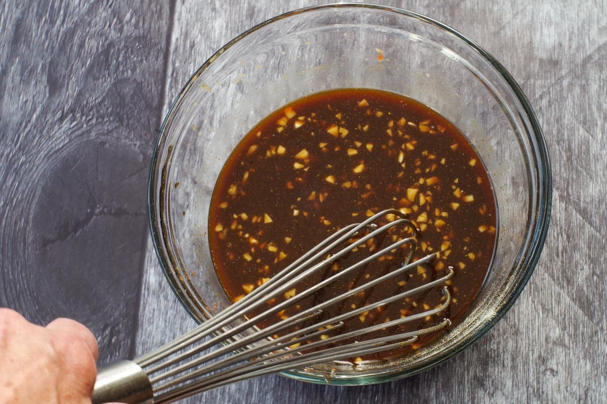 Sauce mixed together in a medium glass bowl with a metal whisk.