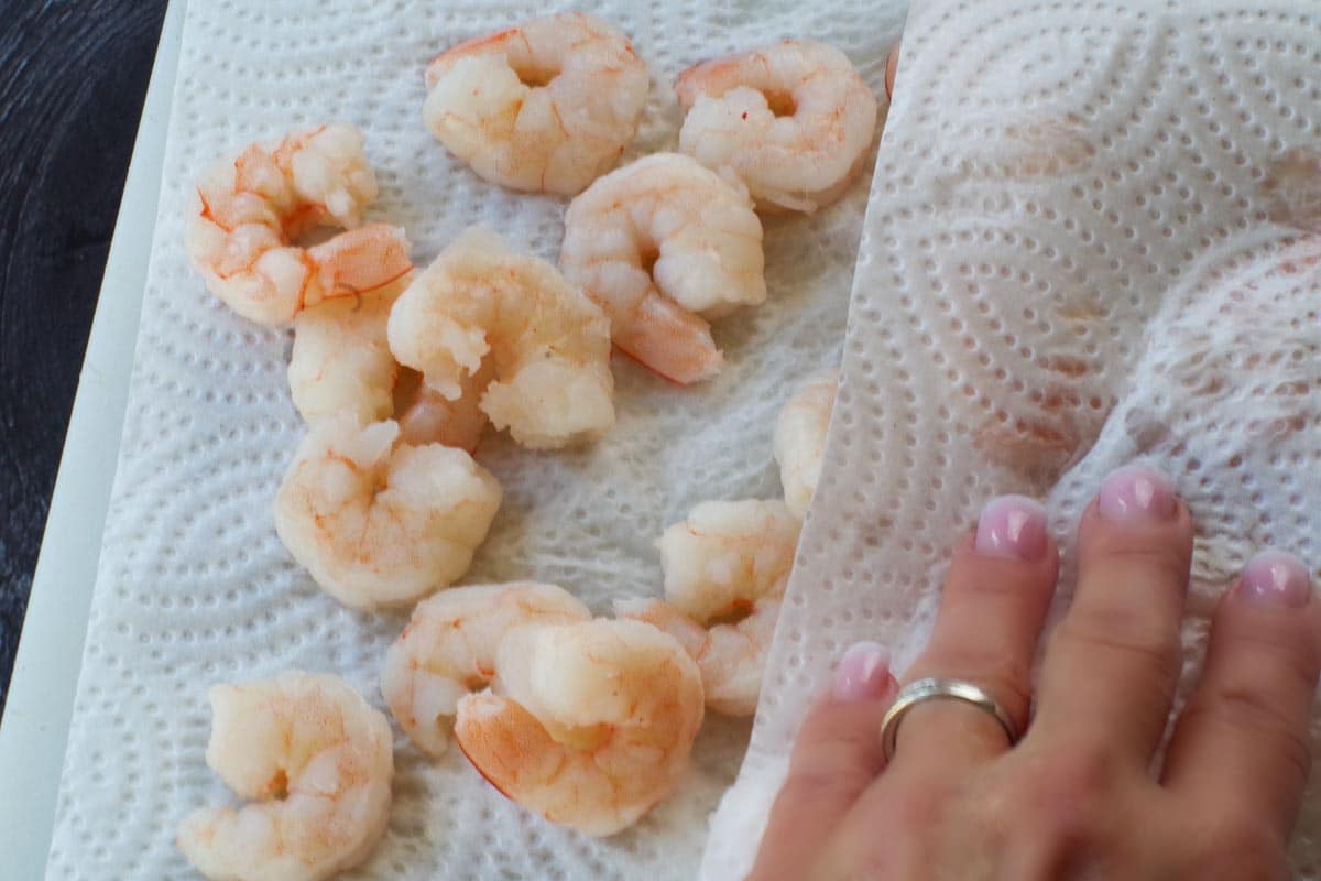 Shrimp being pat dry with paper towel.